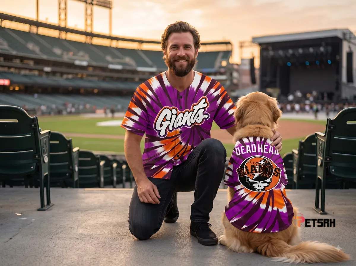 Man and dog wearing matching orange and purple psychedelic tie-dye baseball jerseys in a stadium.