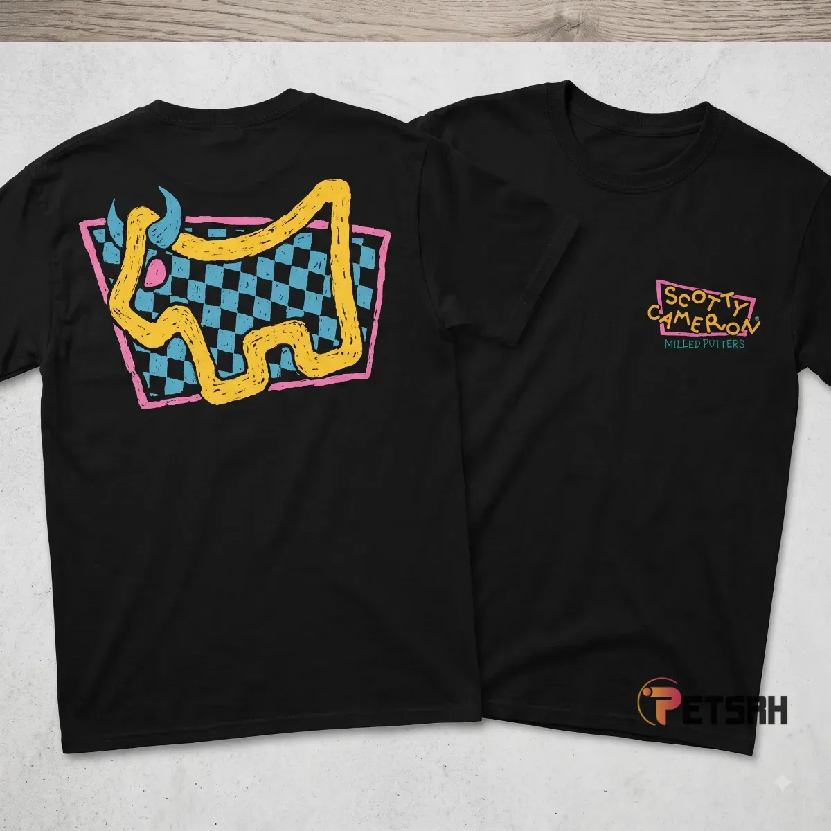 Rear view of the black Scotty Cameron Dog Days Check Bulldog T-Shirt displaying a large stylized yellow bulldog over a blue and black checkered backdrop framed in pink.